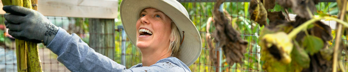 young woman working in garden, looking up smiling